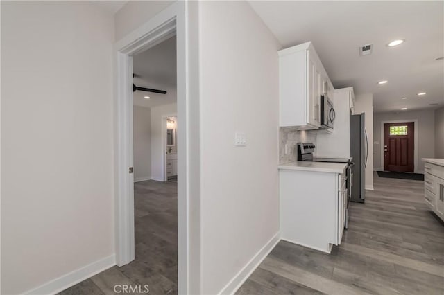 kitchen featuring tasteful backsplash, stainless steel appliances, light wood-type flooring, and white cabinets