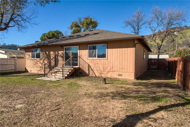 rear view of property with a shingled roof, crawl space, a fenced backyard, and a yard