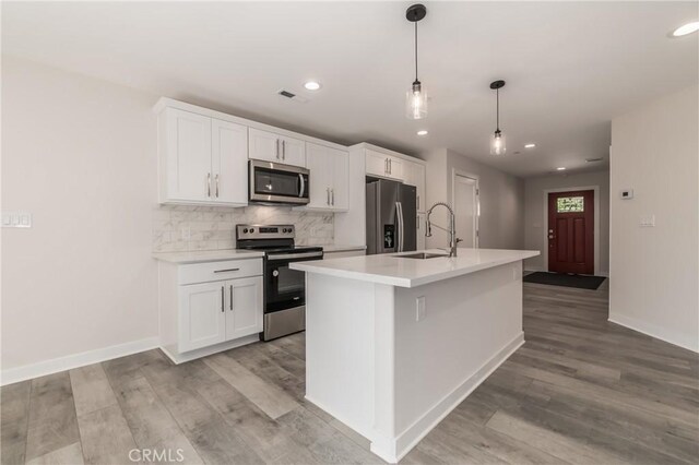 kitchen featuring pendant lighting, stainless steel appliances, an island with sink, white cabinetry, and sink