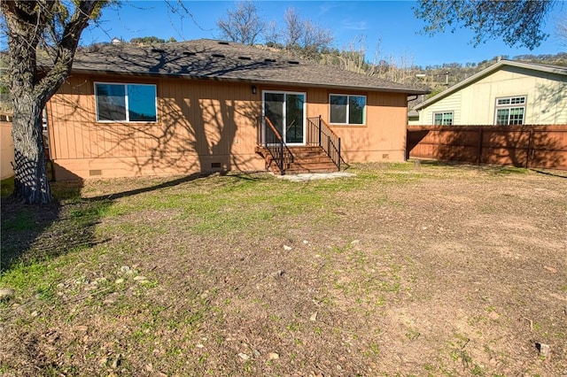 back of property featuring entry steps, a shingled roof, crawl space, fence, and a yard