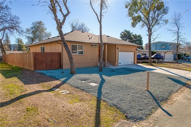 view of front facade featuring a garage, driveway, roof with shingles, and fence