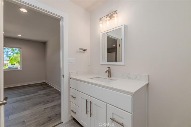 bathroom featuring recessed lighting, baseboards, wood finished floors, and vanity