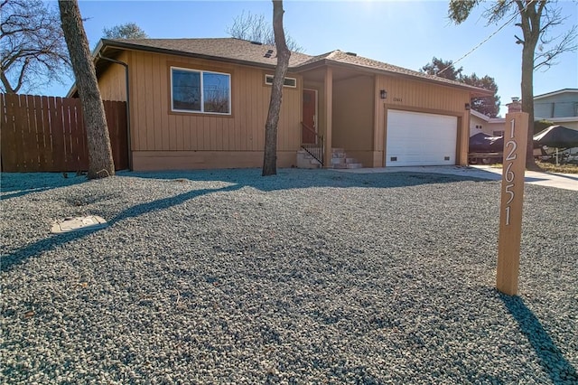 view of front of house with a garage, a shingled roof, fence, and entry steps