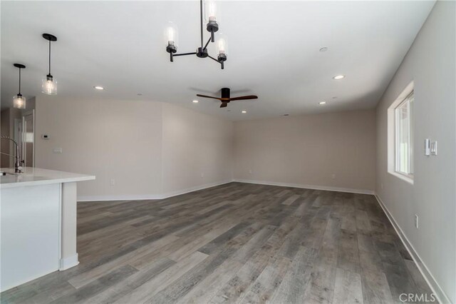 unfurnished living room featuring sink, hardwood / wood-style floors, and ceiling fan with notable chandelier