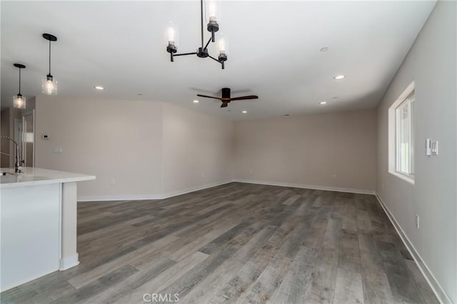 unfurnished living room with hardwood / wood-style flooring, sink, and a notable chandelier