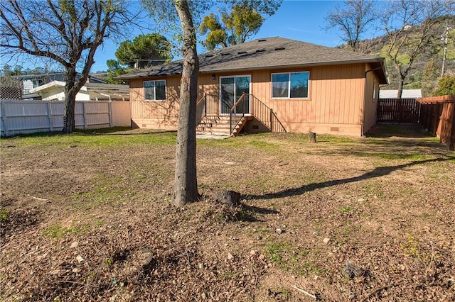 rear view of property with entry steps, a lawn, a fenced backyard, roof with shingles, and crawl space
