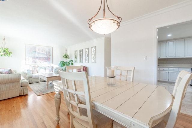 dining area with ornamental molding and light hardwood / wood-style floors