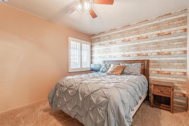 carpeted bedroom featuring wood walls and ceiling fan