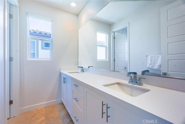 full bath featuring a sink, baseboards, tile patterned floors, and double vanity