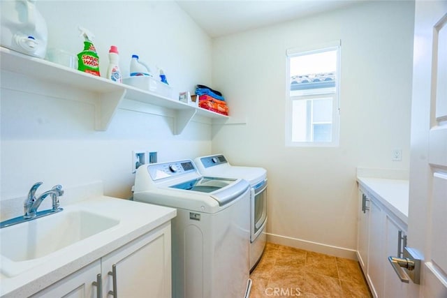 washroom featuring cabinet space, light tile patterned flooring, a sink, baseboards, and washing machine and dryer