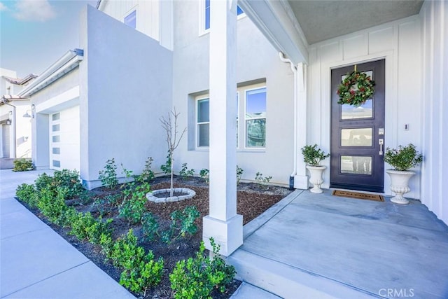 property entrance featuring a garage, stucco siding, and covered porch