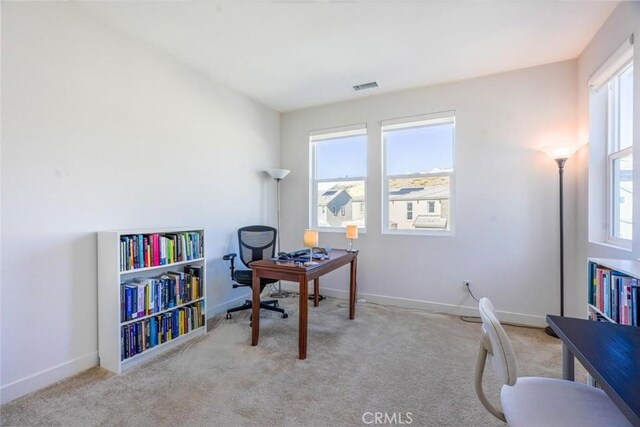 carpeted office space featuring baseboards, visible vents, and a healthy amount of sunlight