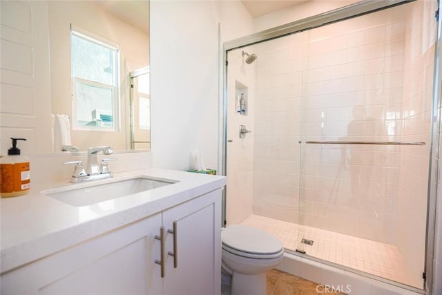 bathroom with a shower with door, tile patterned floors, vanity, and toilet