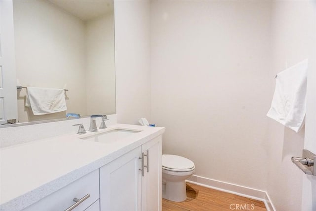 bathroom featuring vanity, baseboards, toilet, and wood finished floors