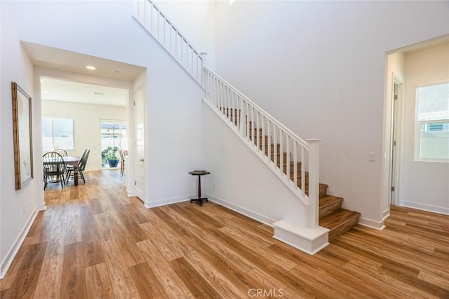 staircase featuring baseboards, recessed lighting, wood finished floors, and a wealth of natural light