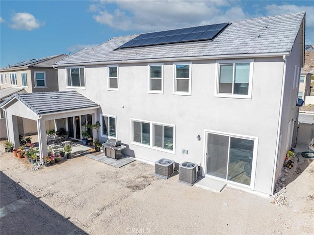 back of property with central AC, solar panels, and a patio