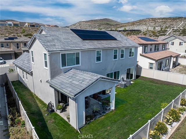 back of property with a residential view, a mountain view, roof mounted solar panels, and stucco siding