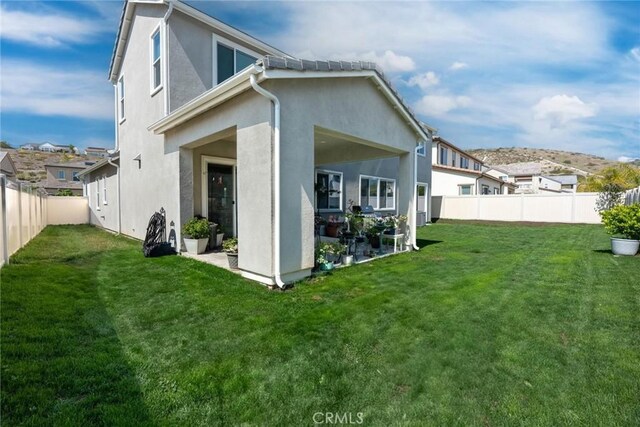 back of property featuring a lawn, a fenced backyard, and stucco siding
