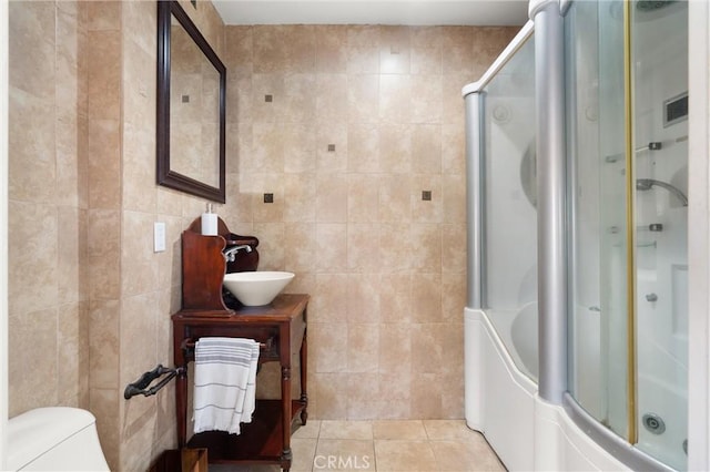 full bathroom featuring a shower with shower door, toilet, tile walls, and tile patterned flooring