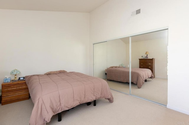 bedroom featuring lofted ceiling, a closet, and light carpet