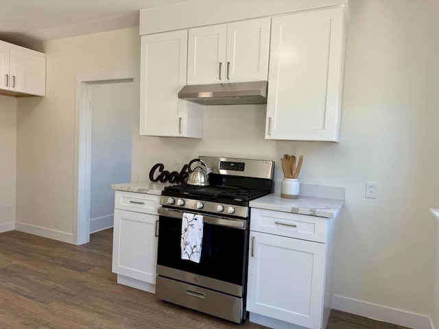 kitchen with light stone countertops, white cabinets, stainless steel gas range, and dark hardwood / wood-style floors