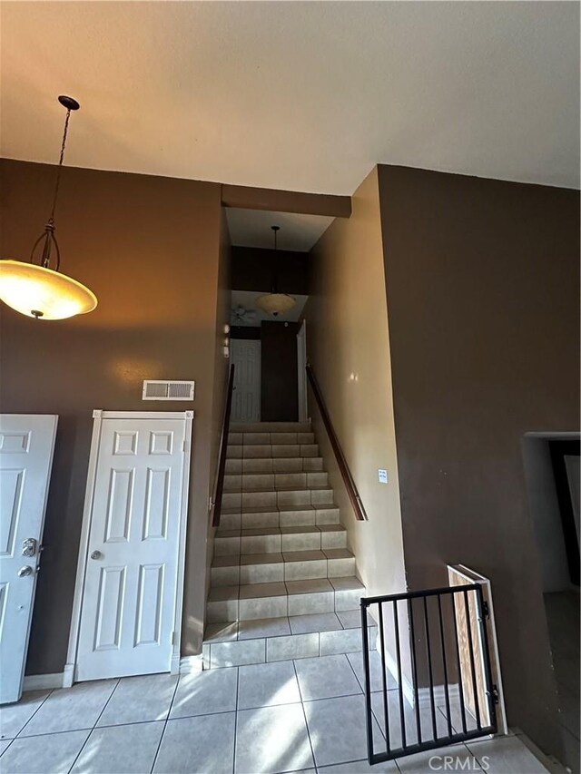 stairway with tile patterned floors, baseboards, and visible vents