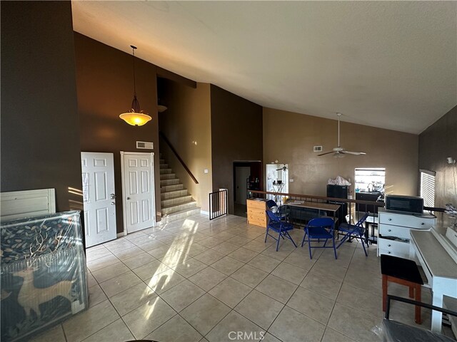 dining room with ceiling fan, high vaulted ceiling, and light tile patterned flooring