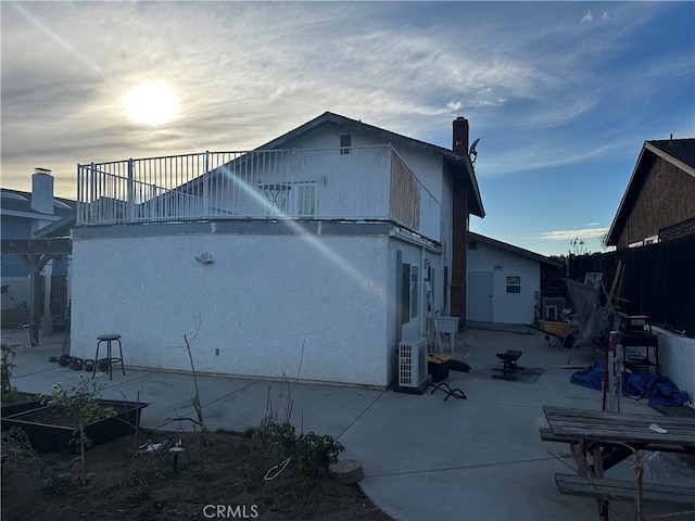 back of property with ac unit, a patio area, fence, a balcony, and stucco siding