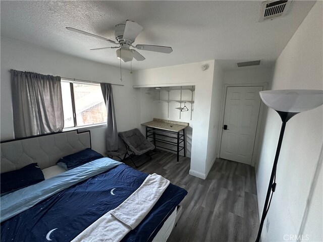 bedroom with dark wood-type flooring, a textured ceiling, and ceiling fan