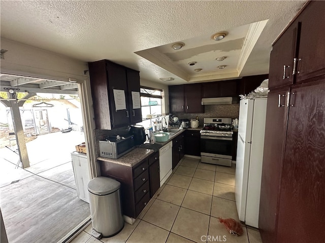 kitchen with a raised ceiling, a textured ceiling, under cabinet range hood, a sink, and stainless steel appliances