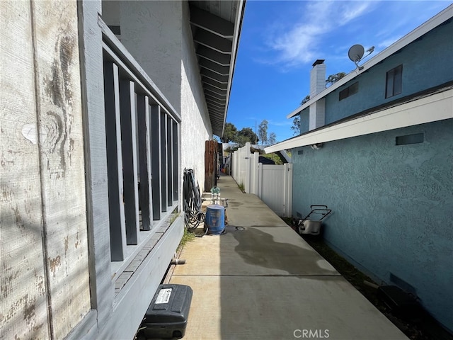 view of property exterior with stucco siding, a patio area, and fence