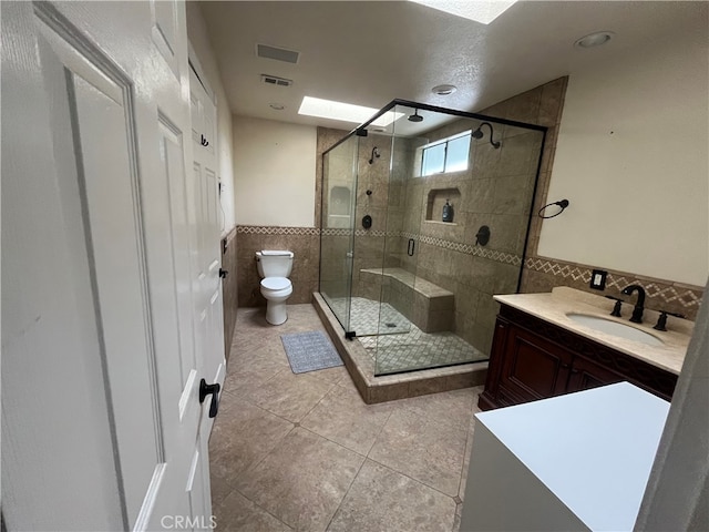 full bathroom with visible vents, tile walls, tile patterned flooring, a stall shower, and toilet