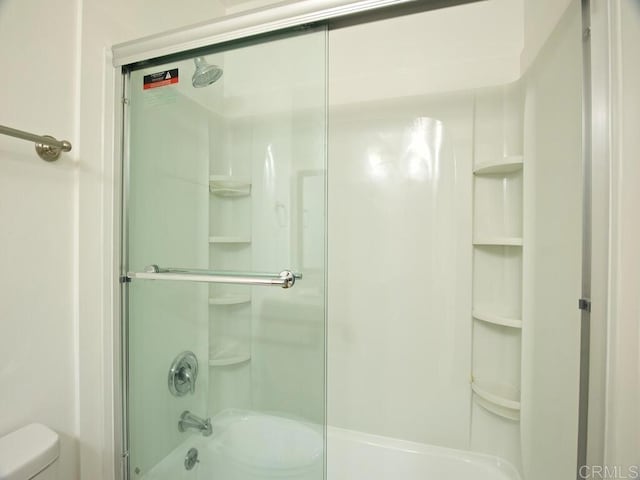 bathroom featuring bath / shower combo with glass door and toilet