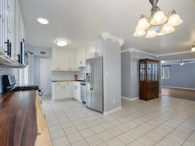 kitchen featuring ceiling fan with notable chandelier, stainless steel appliances, crown molding, and white cabinetry