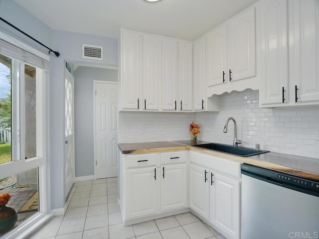 kitchen with wooden counters, white cabinets, sink, stainless steel dishwasher, and light tile patterned flooring