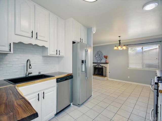 kitchen with sink, white cabinets, hanging light fixtures, and appliances with stainless steel finishes