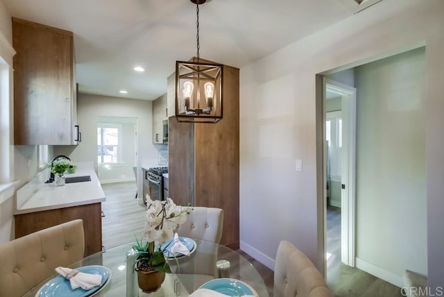 dining room with sink, a notable chandelier, and light wood-type flooring