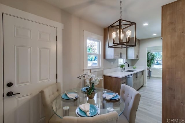 dining space with a chandelier, sink, light hardwood / wood-style flooring, and a wealth of natural light