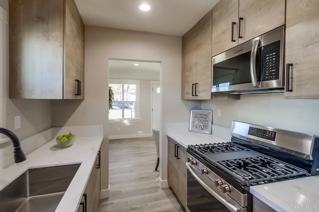 kitchen featuring appliances with stainless steel finishes, sink, and light hardwood / wood-style floors