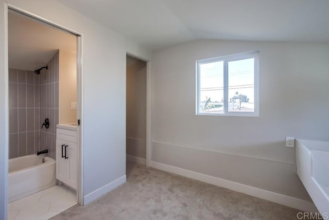 bathroom featuring tiled shower / bath, lofted ceiling, and vanity