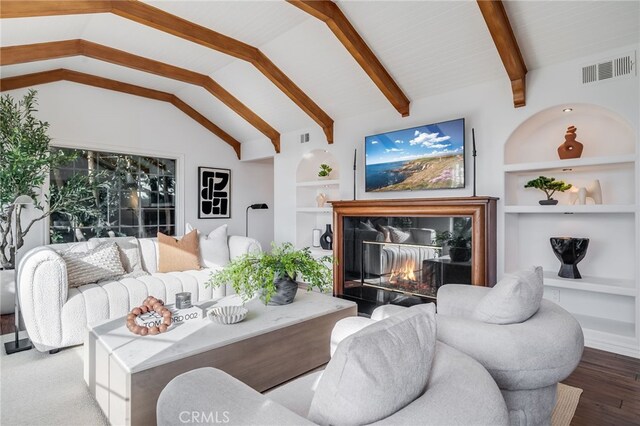 living room featuring hardwood / wood-style flooring, vaulted ceiling with beams, a fireplace, and built in shelves