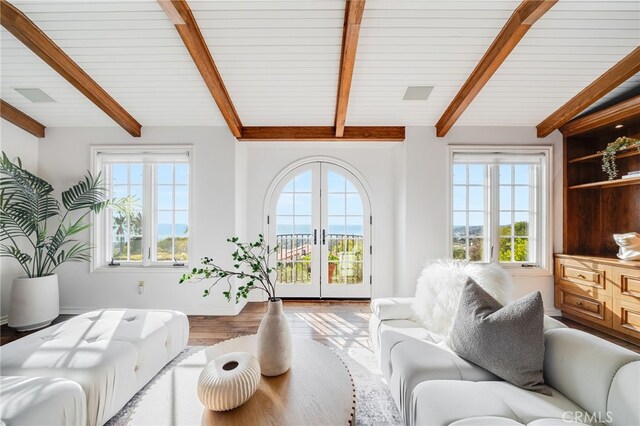 living room with plenty of natural light, light hardwood / wood-style floors, french doors, and beamed ceiling