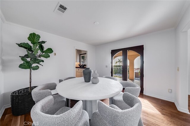 dining area with crown molding, hardwood / wood-style floors, and french doors