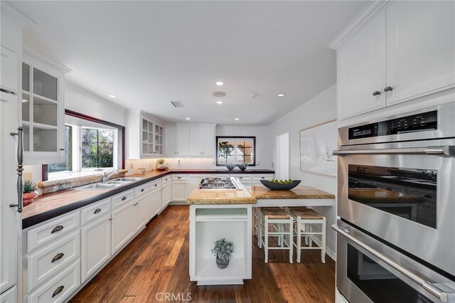 kitchen with appliances with stainless steel finishes, sink, white cabinets, and a breakfast bar