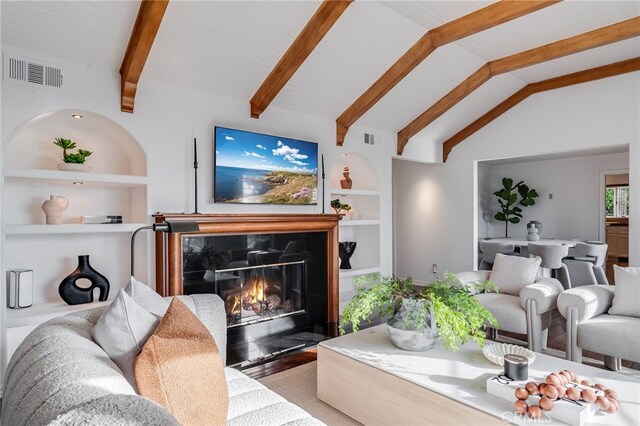 living room featuring lofted ceiling with beams, a high end fireplace, and built in shelves