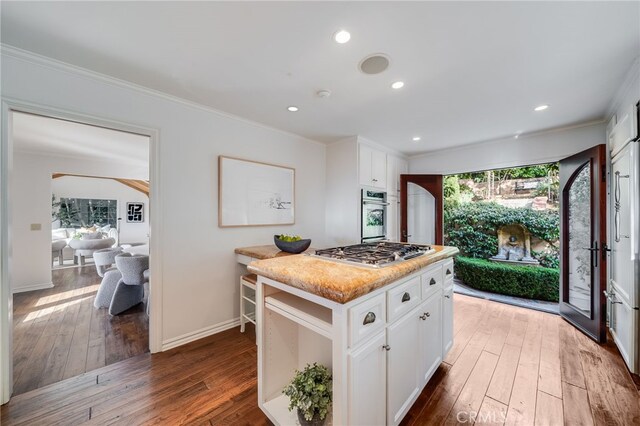 kitchen featuring stainless steel appliances, a kitchen island, dark hardwood / wood-style floors, and white cabinets