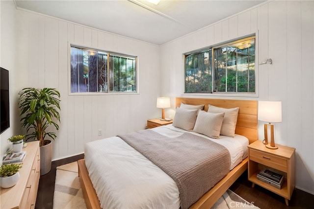 bedroom featuring multiple windows and wood walls