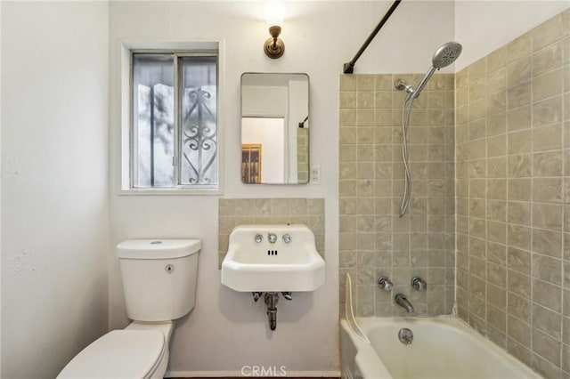 bathroom featuring tiled shower / bath combo and toilet