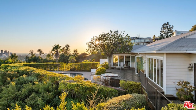 yard at dusk with a sunroom and a swimming pool side deck