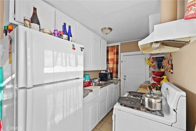 kitchen featuring light tile patterned floors, washer / dryer, white cabinetry, white refrigerator, and sink